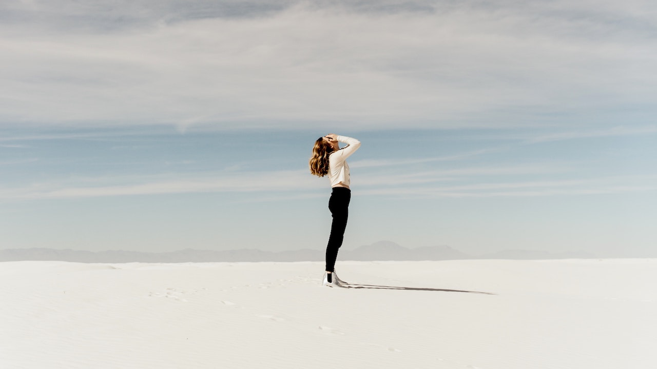 Woman standing in the middle of nowhere looking up while covering her face